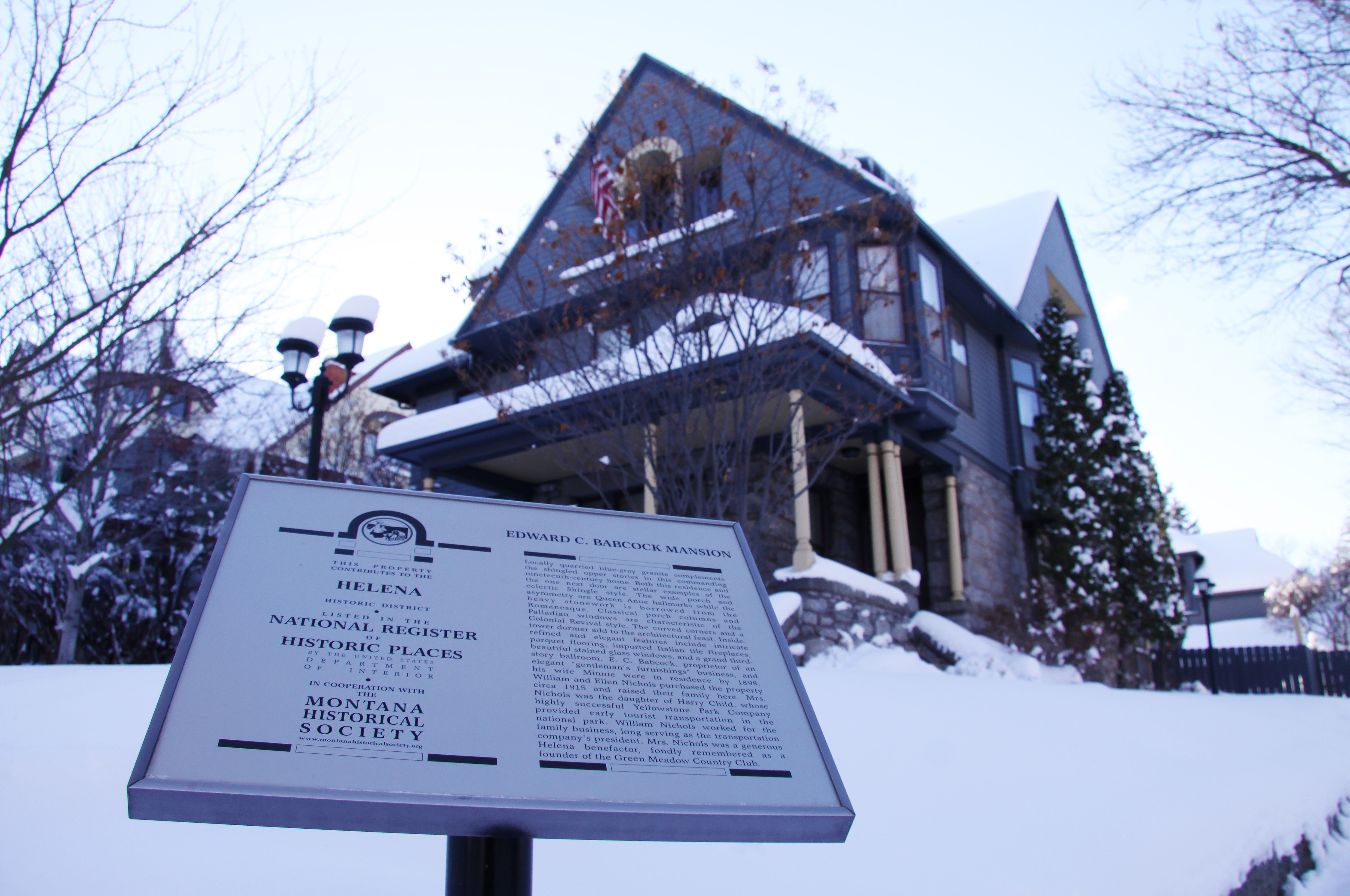View of a Queen Anne style house in winter with a National Register sign in the front yard.
